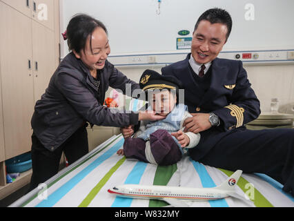 The mother, right, of the four-year-old legless boy Li Haifeng helps her son put on the hat of a pilot of China Eastern Airlines, right, at Zhongnan H Stock Photo