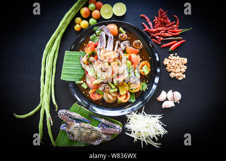 Seafood salad spicy with fresh shrimp crab cockles served on black plate fresh vegetables herbs and spices ingredients with chilli tomato peanut garli Stock Photo