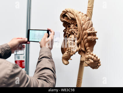 A visitor takes photos of an artwork of Dongyang wood carving created by Frenchman Guilhem Bouissou in Dongyang city, east China's Zhejiang province, Stock Photo