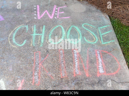 the words "We Choose Kind" written with sidewalk chalk on gray concrete pavement background Stock Photo