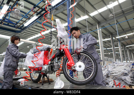 --FILE--Chinese workers assemble motorbike engines on the assembly line ...