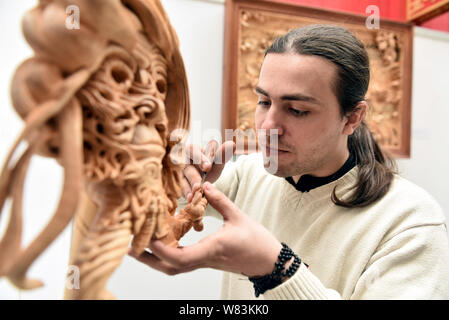 Frenchman Guilhem Bouissou creates an artwork of Dongyang wood carving in Dongyang city, east China's Zhejiang province, 12 November 2016.   Frenchman Stock Photo