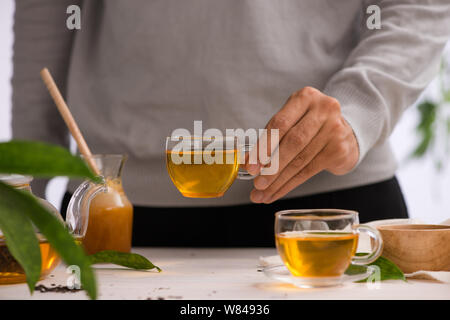 Male hands holding cup of tea glass on light background Stock Photo