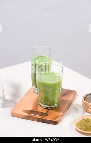 Matcha green tea iced latte or cocktail in tall glass on white background