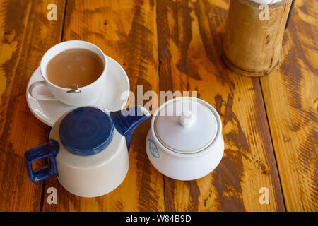 Traditional indian tea set with masala chai on wooden background. Composition from teapot, sugarbowl and cup on table. Top veiw. Stock Photo