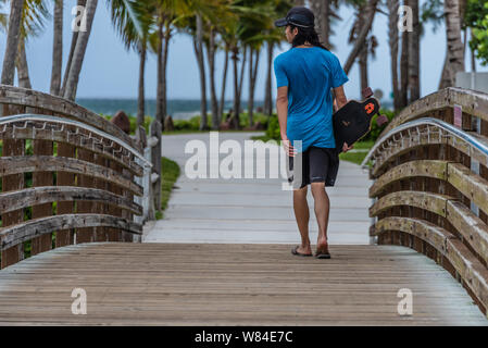 Teen skateboarder crossing a footbridge over a lagoon at DuBois Park on the Jupiter Inlet at Jupiter, Florida in Palm Beach County. (USA) Stock Photo