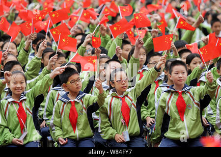 Young Chinese students wave national flags during a gala to celebrate the 80th anniversary of the victory of the Long March trek at a primary school i Stock Photo