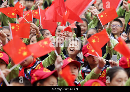 Young Chinese students wave national flags during a gala to celebrate the 80th anniversary of the victory of the Long March trek at a primary school i Stock Photo