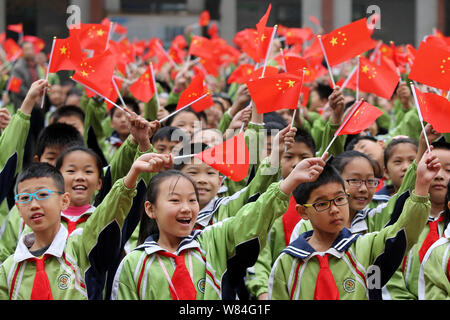 Young Chinese students wave national flags during a gala to celebrate the 80th anniversary of the victory of the Long March trek at a primary school i Stock Photo