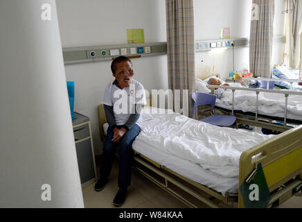Chinese villager Xia Yuanhai, left, who has an alien-like deformed face, sits in a ward at Chongqing Xinqiao Hospital in Chongqing, China, 25 October Stock Photo