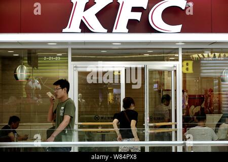 --FILE--Pedestrians walk past a fastfood restaurant of KFC in Huaian city, east China's Jiangsu province, 10 September 2016.   Investors who were look Stock Photo