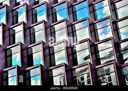 Modern cubist façade of apartment building with glass windows, strong architectural detail and reflections Stock Photo