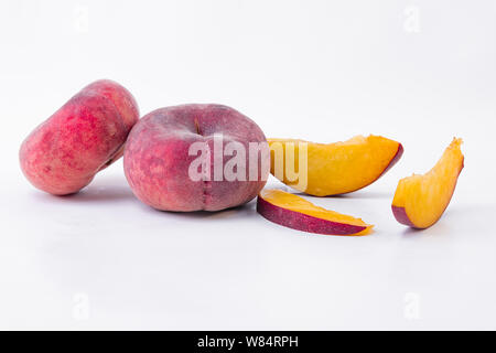 Whole flat peach and slices of flat peach - Ripe flat peach - On a white background - Close-up Stock Photo