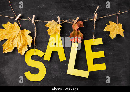 Autumn discount letters from yellow paper and dry leaves on a black chalk board. Autumn sale concept. Seasonal Offer Stock Photo