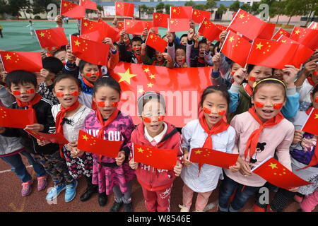 Young students wave Chinese national flags they made to celebrate the upcoming National Day at a primary school in Donghai county, Lianyungang city, e Stock Photo