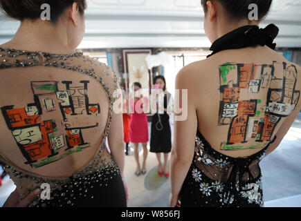 Chinese models display the layouts of apartments on their backs at a promotional event for a luxury residential project in Taiyuan city, north China's Stock Photo