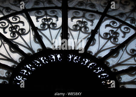 An ornate wrought iron and glass window over a doorway. Stock Photo