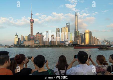 --FILE--Tourists visiting the promenade on the Bund to take pictures of the cityscape of the Lujiazui Financial District with the Oriental Pearl TV To Stock Photo
