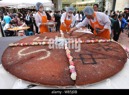 An employee from a local food company makes Chinese characters with sesame meaning 'Happy Mid-Autumn Festival' on the giant mooncake with a diameter o Stock Photo
