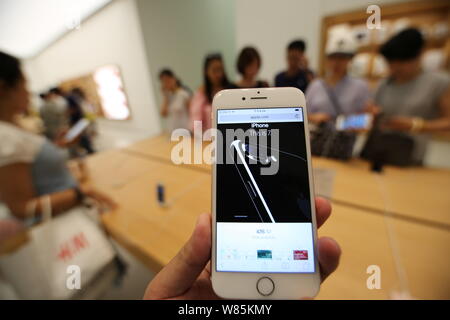 --FILE--A customer tries out an iPhone 7 smartphone at an Apple Store in Qingdao city, east China's Shandong province, 16 September 2016.   A company Stock Photo