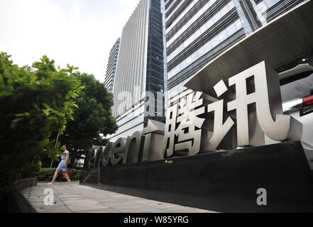 --FILE--A pedestrian walks past the logo of Tencent in front of the headquarters building of Tencent in Shenzhen city, south China's Guangdong provinc Stock Photo