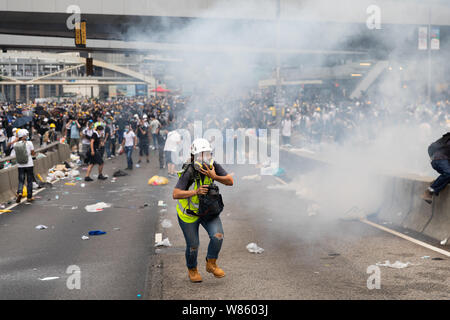 12th June 2019 During an Anti Extradition Bill protest outside the government offices in Admiralty. A journalist running for cover as tear gas canisters are fired sending protesters frantically running from the area. Stock Photo