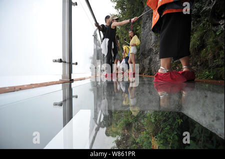 Tourists walk on the 100-meter-long and 1.6-meter-wide glass skywalk on the cliff of Tianmen Mountain (or Tianmenshan Mountain) in Zhangjiajie Nationa Stock Photo