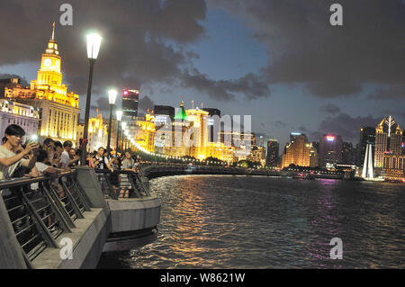 Tourists visit the Bund along illuminated colonial buildings in Puxi, Shanghai, China, 8 August 2016. Stock Photo