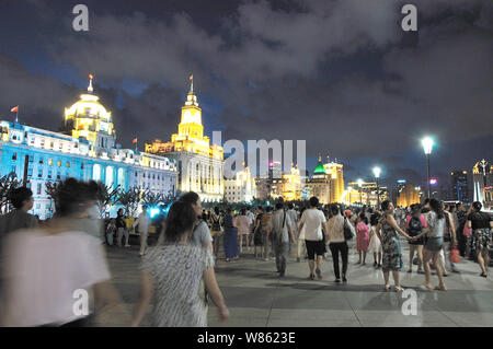 Tourists crowd the promenade on the Bund along illuminated colonial buildings in Puxi, Shanghai, China, 8 August 2016. Stock Photo