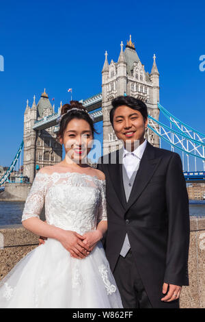 England, London, Tower Bridge, Chinese Couple in Wedding Costume Standing in Front of Tower Bridge Stock Photo
