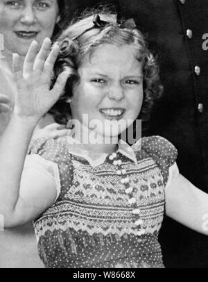 Vintage photo of American child film star Shirley Temple (1928 – 2014). The image was captured on June 24 1938 as the young actress waved to onlookers after she left the White House following a meeting with US President Franklin D Roosevelt. During their conversation she told the President how she had lost a tooth the night before when it fell out as she ate a sandwich. Stock Photo