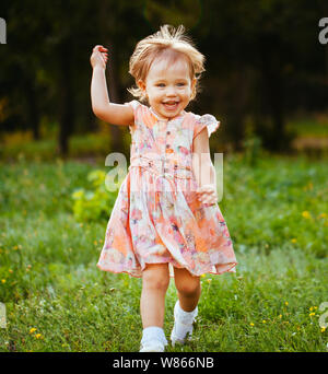 Happy cute little girl running on the grass in the park. Happiness. Stock Photo