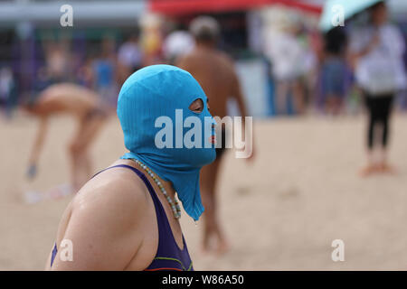 A Chinese woman wearing a facekini walks out of the water at a