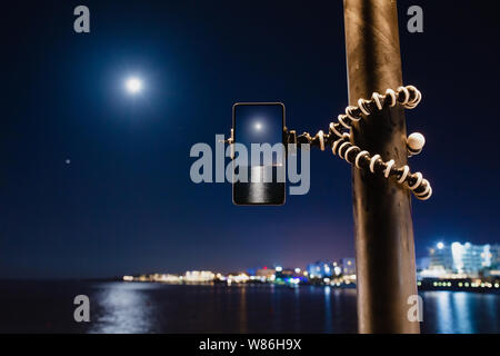 Using smartphone on flexible tripod to making the photo of sea night landscape Stock Photo