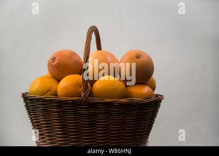 wicker basket with oranges and grapefruits on white background Stock Photo