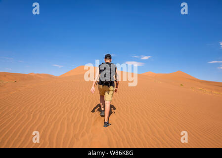 Tourist walks on the scenic dunes of Sossusvlei in the Namib desert, Namibia