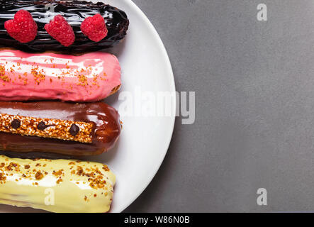 Delicious eclairs of different flowers on grey stone background with copy space Stock Photo