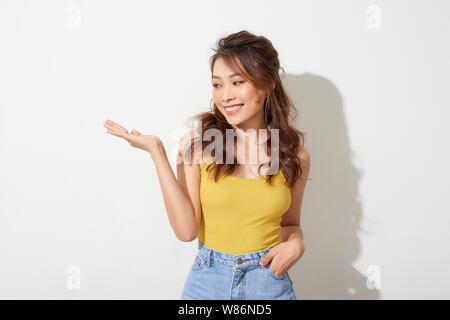 Smiling asian woman showing open hand palm to to the copy space for product or something Stock Photo