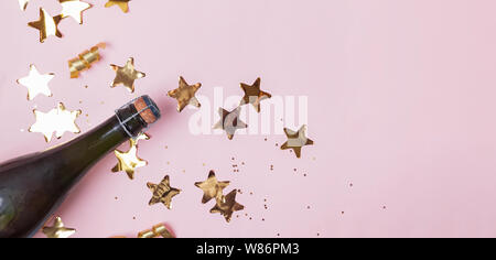 Champagne and star shaped gold confetti on the pink background. Party concept. Banner Stock Photo