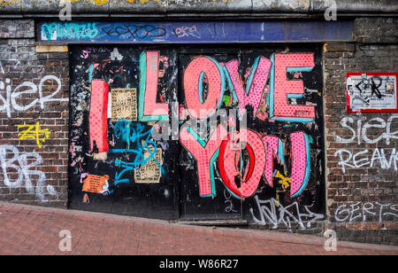 Colourful graffiti on wall under Brighton railway station spelling I Love You in bright pink lettering Stock Photo