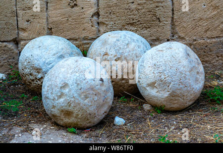 Group of ancient stone balls used in medieval cannons and preserved in the square of a castle Stock Photo