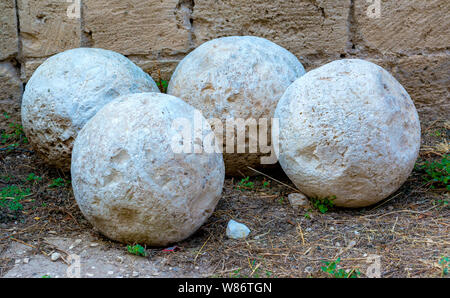 Group of ancient stone balls used in medieval cannons and preserved in the square of a castle Stock Photo