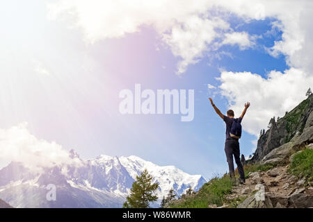 Young man in the mountains standing with his hands raised Stock Photo