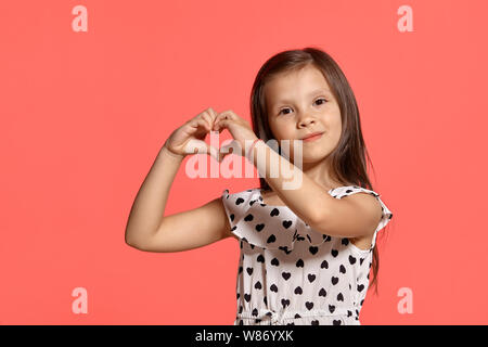 Close-up studio shot of beautiful brunette little girl posing against a pink background. Stock Photo