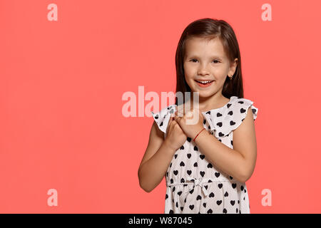 Close-up studio shot of beautiful brunette little girl posing against a pink background. Stock Photo