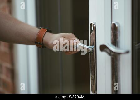 Closeup shot of a person holding a door knob and opening the door Stock Photo