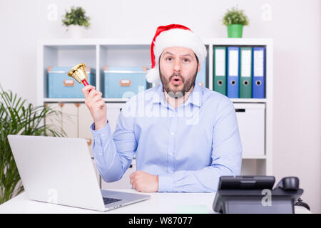 Attractive man is ringing the bell at christmas time. Business, christmas and new year celebration concept. Stock Photo