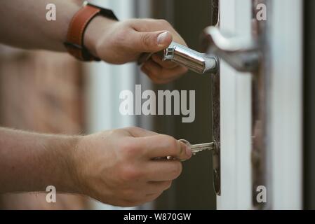 Closeup shot of a person holding a door knob and opening the door with a key Stock Photo