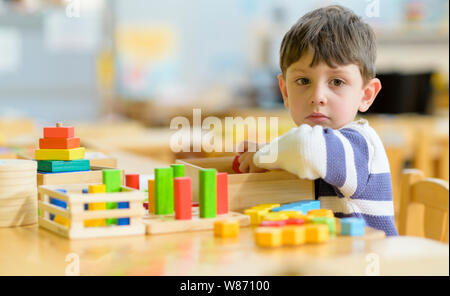 Cute little boy playing alone at kindergarten with construction toy Stock Photo