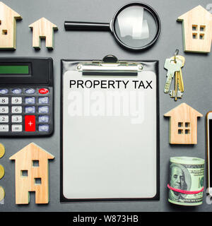 Table with wooden houses, calculator, coins, magnifying glass with the word Property Tax. Property taxes. Calculation of interest on housing tax. Pena Stock Photo